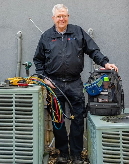 A&K Service Inc. HVAC technician standing beside newly installed air conditioning units